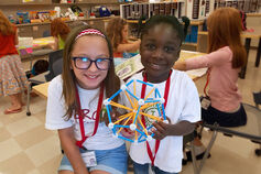Two children holding a polyhedron they assembled at the library.